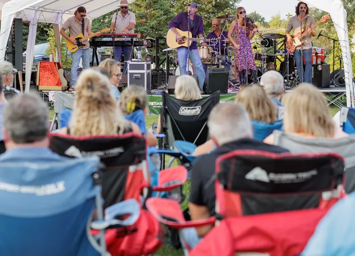 A band playing under a tent on the patio lawn as the crowd settles into lawn chairs
