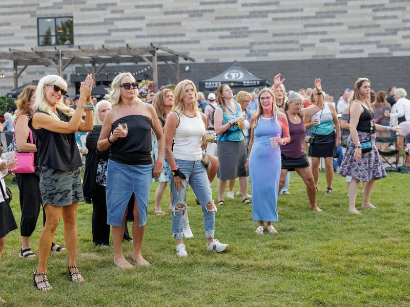Women dancing and clapping on the lawn during an evening concert