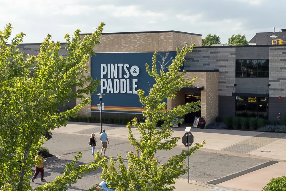 The Pints & Paddle sign on the front of the building, framed by trees