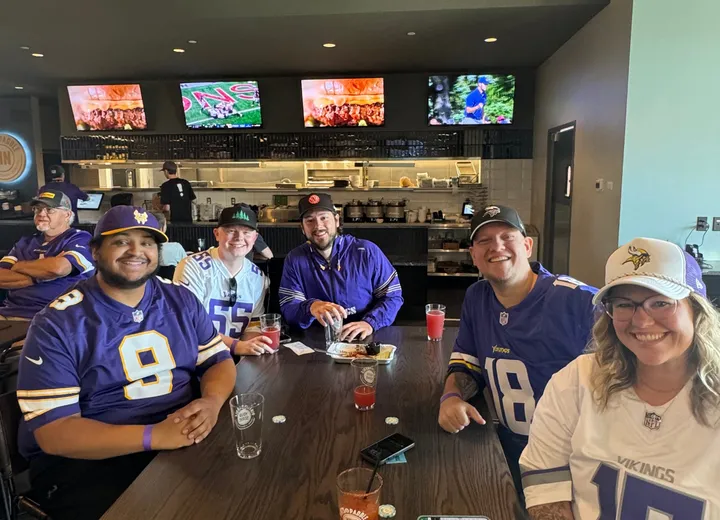 Five friends in Vikings jerseys around a table in front of the kitchen counter