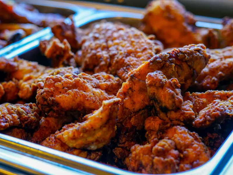 A close-up of golden, crispy fried chicken tenders piled in a stainless chafer pan