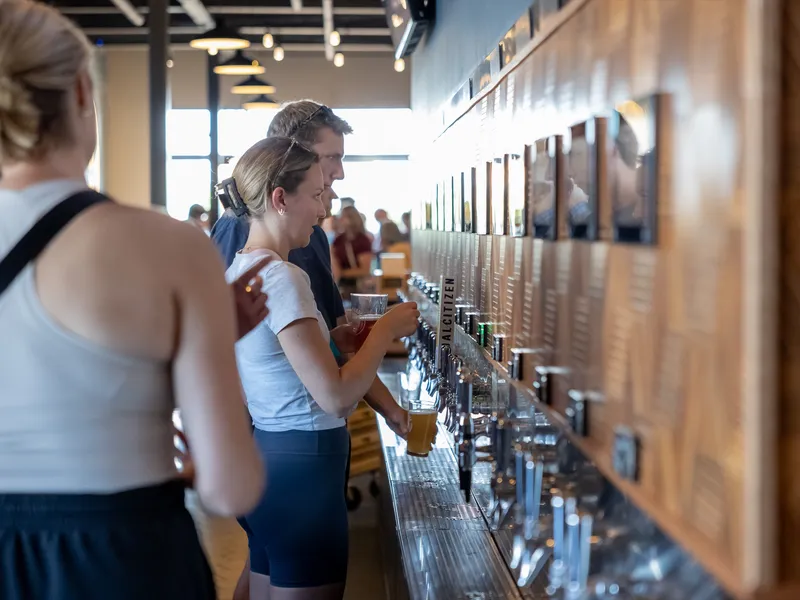 Guests pouring their own beer at the self-serve tap wall