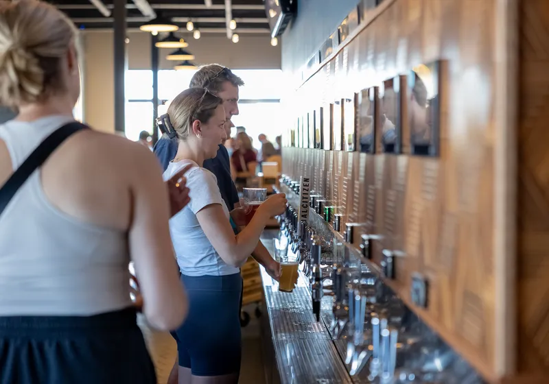 Guests pouring their own beer at the self-serve tap wall