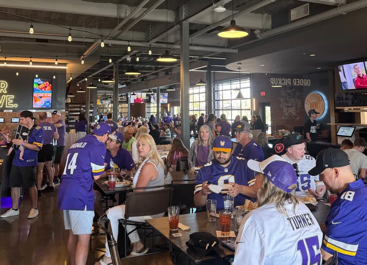 The main level packed with fans in purple Vikings jerseys at the long tables on a Sunday