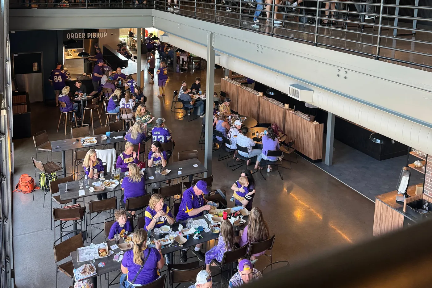Looking down from the mezzanine on the main level full of fans in purple at the long tables