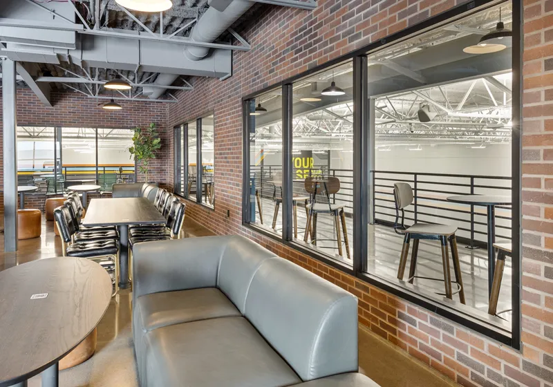 The north mezzanine lounge with a leather sofa and window bays looking down onto the indoor courts