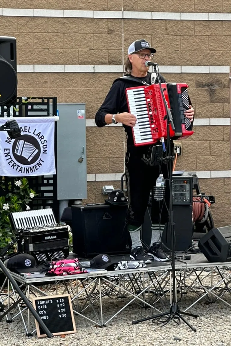 An accordion player performing against the brick wall on the patio