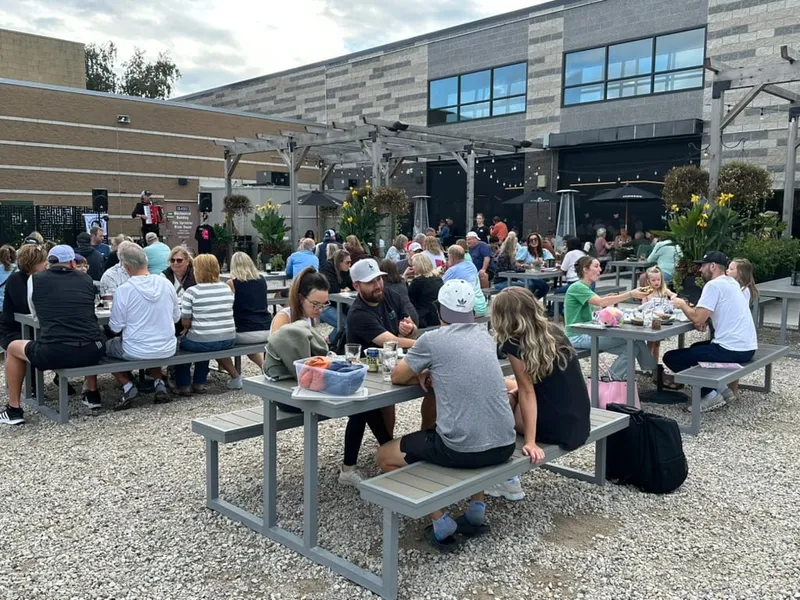The patio picnic tables full of guests at Oktoberfest, the building and pergola behind
