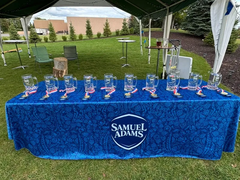 A row of glass steins with ribbons lined up on the Samuel Adams table before the stein hoist