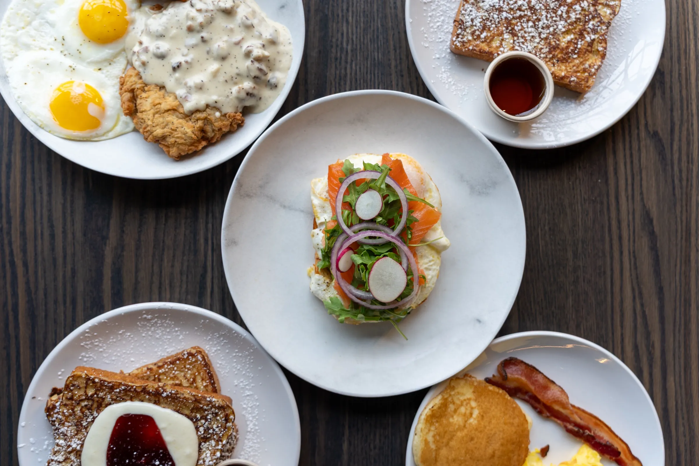 Five breakfast plates from above, with smoked salmon toast in the center