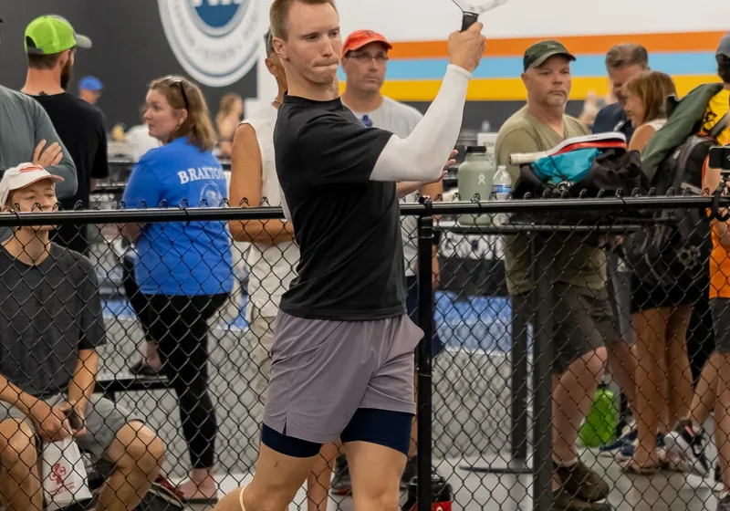 A player follows through on a forehand in front of the fence