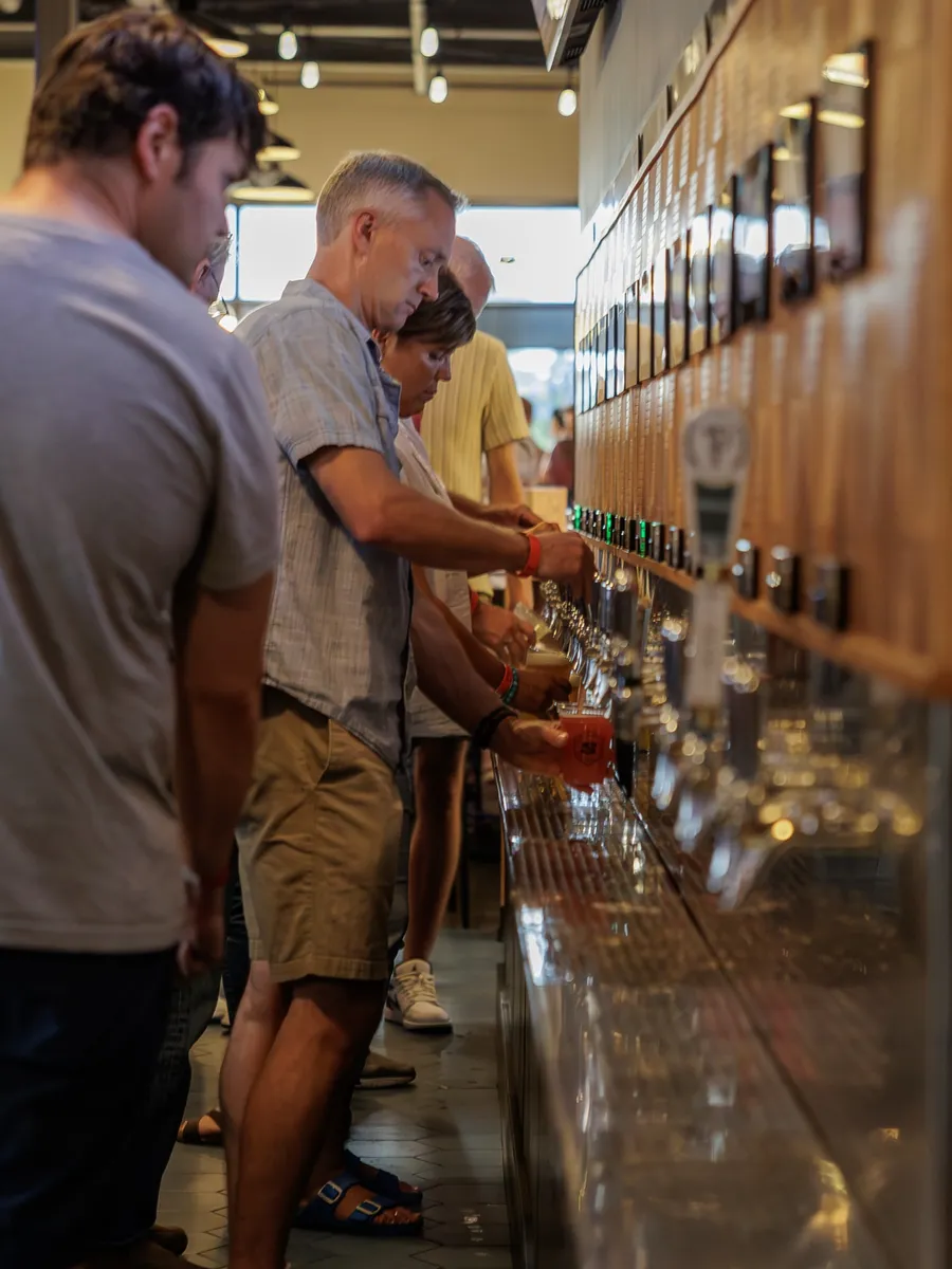 Guests pouring their own beers at the self-serve tap wall