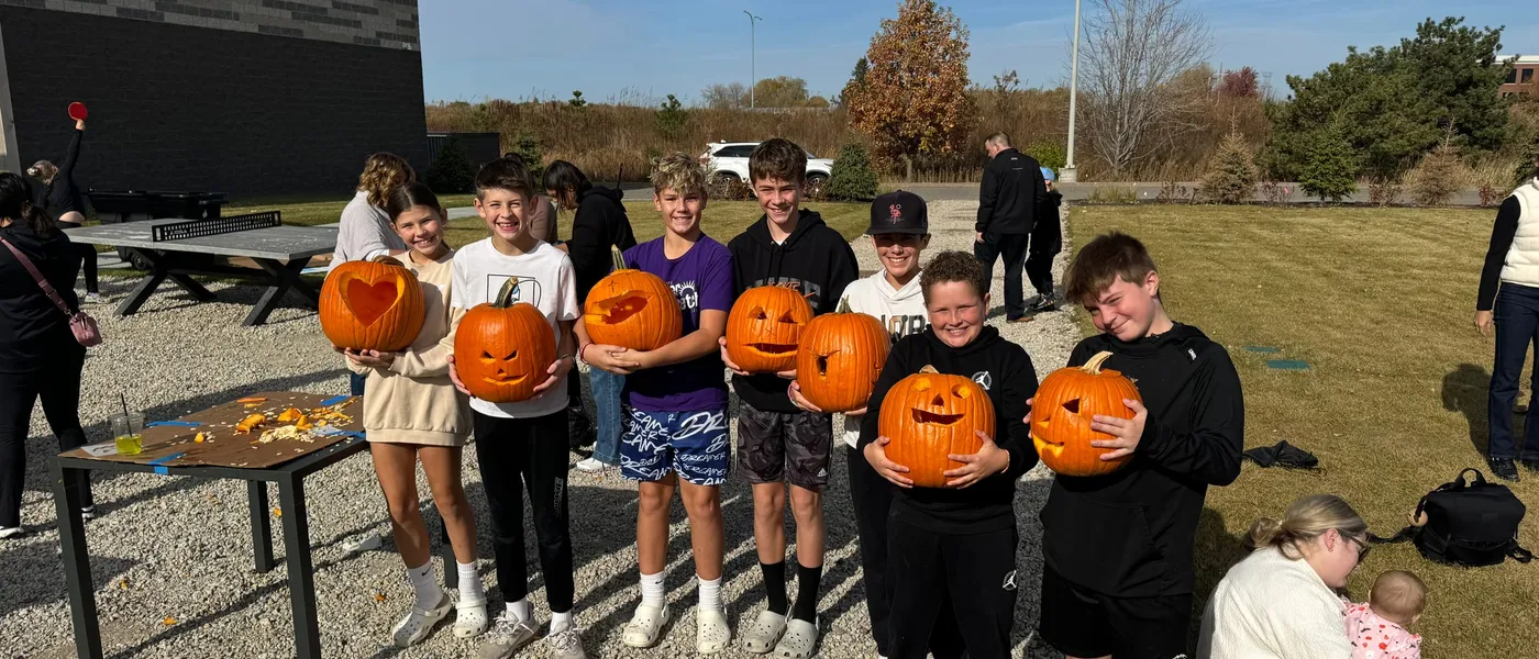 A line of kids holding up their carved pumpkins on the patio