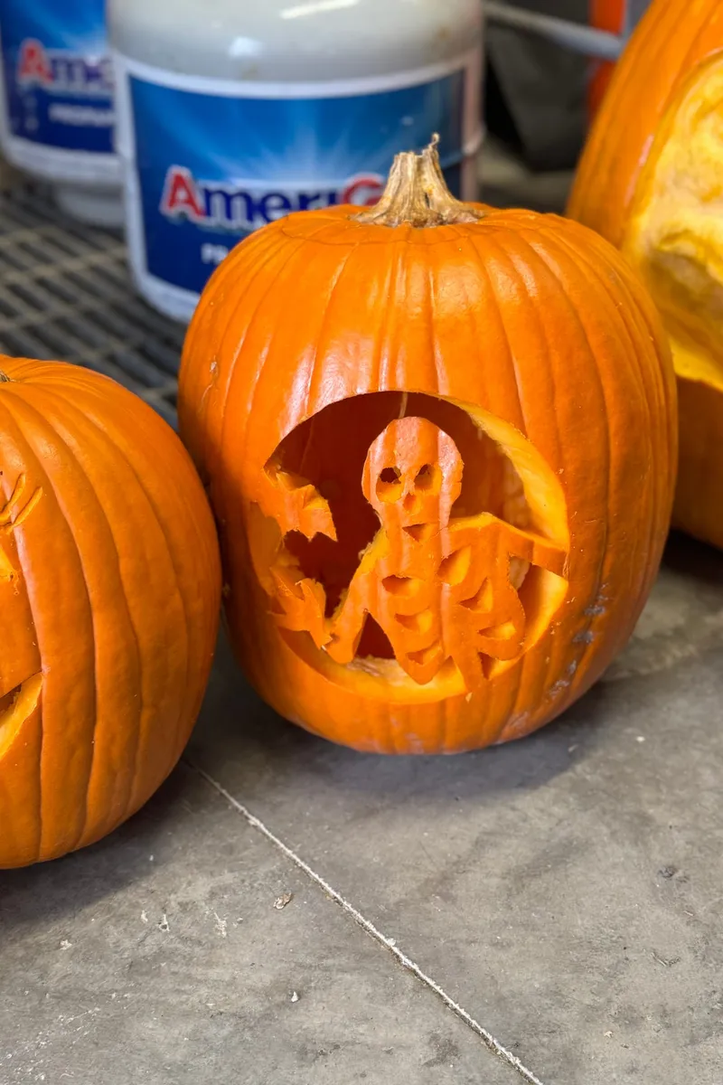 A pumpkin carved with a skeleton, on a patio table