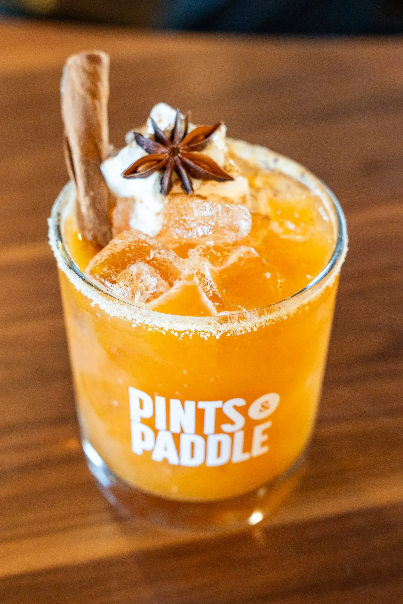 An orange Pumpkin Pie Smash over ice in a Pints & Paddle rocks glass, garnished with a cinnamon stick and star anise.
