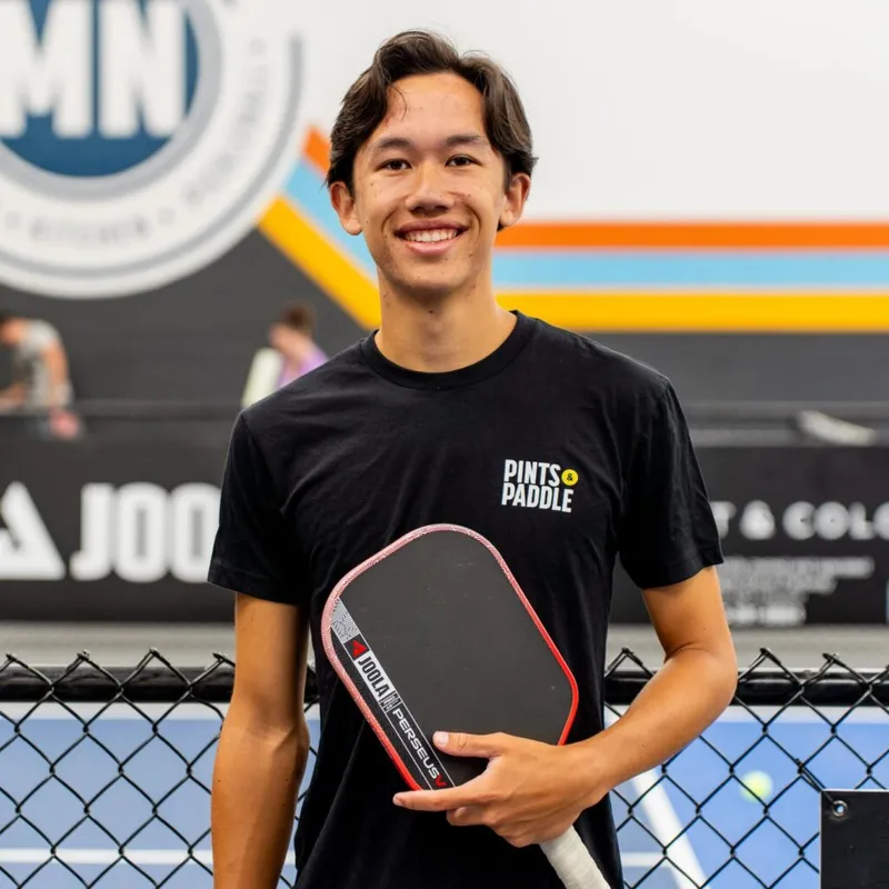 Sammy Lee smiling and holding a paddle on the courts at Pints & Paddle