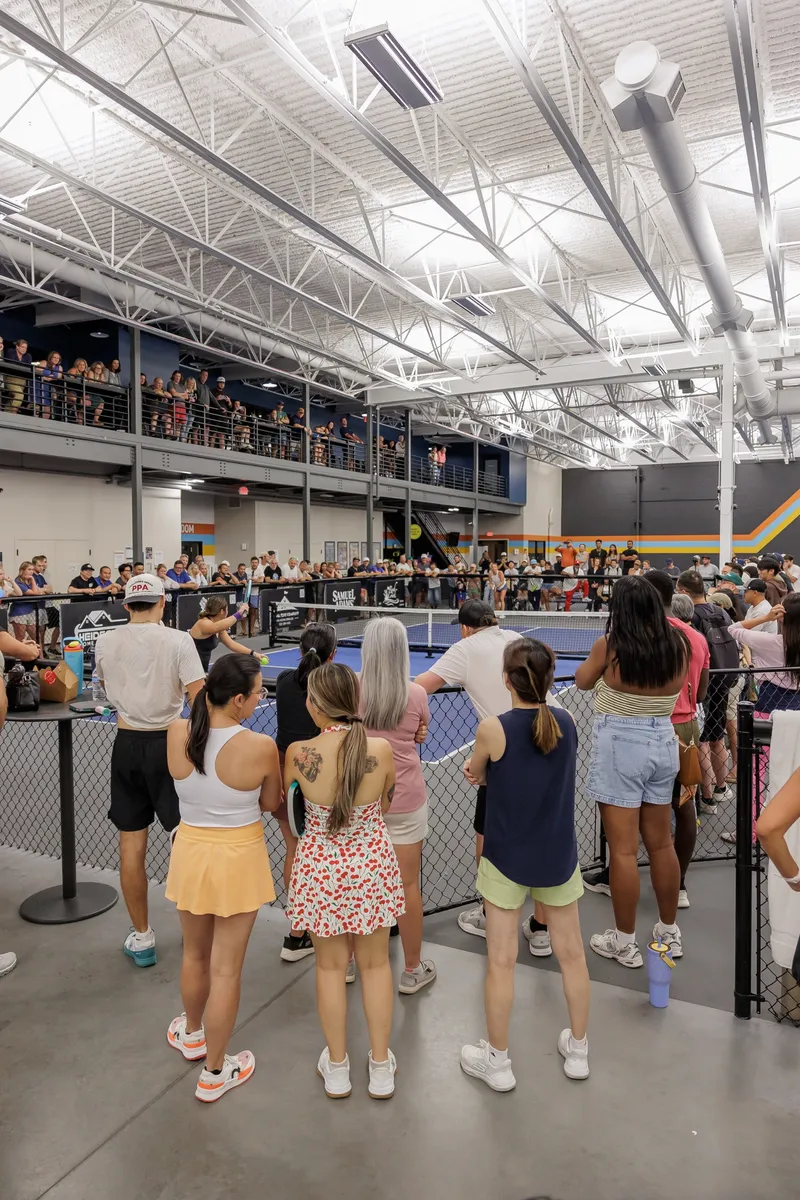 Spectators lean on the court rail with the mezzanine balcony packed above